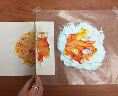 shaving cream on a paper with orange and yellow paint to show the sun for a solar eclipse activity 
